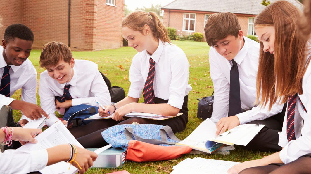 Group of secondary school pupils sat outside working