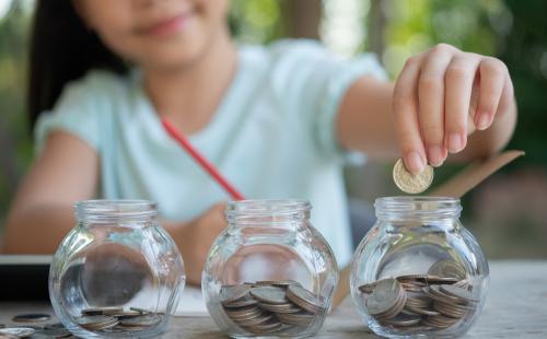 Child putting money in jars - Freepik / jcomp