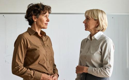 Two teachers having a conversation at the front of a classroom