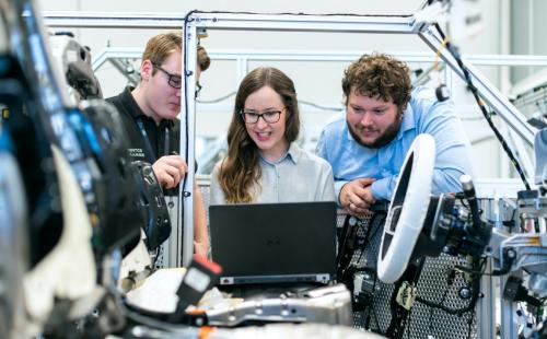 Three engineers having a discussion in front of a laptop