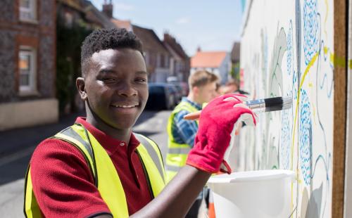 Young man painting a mural on a wall
