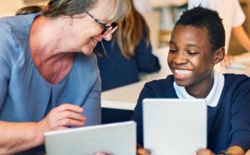 Teacher and pupil using tablets in a classroom