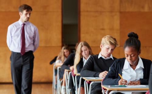 An invigilator and students in an exam hall
