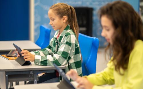 Female pupils working on tablet computers