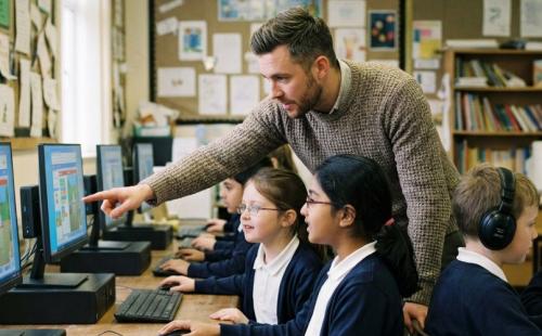 Teacher with pupils looking at computers