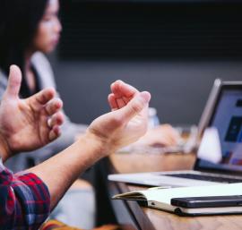 Laptop on a desk with people in conversation