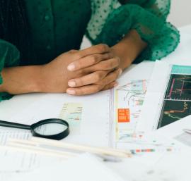 Desk with laptop, charts, and a magnifying glass