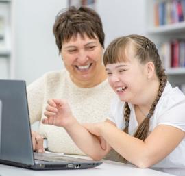Child and adult sitting at a desk using a computer